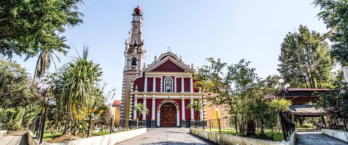 A church with a tall bell tower and a red facade.