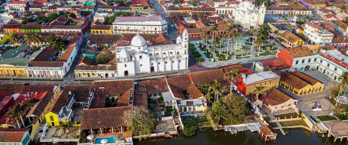 A coastal city with colorful buildings, a prominent white church, and a marina with boats.