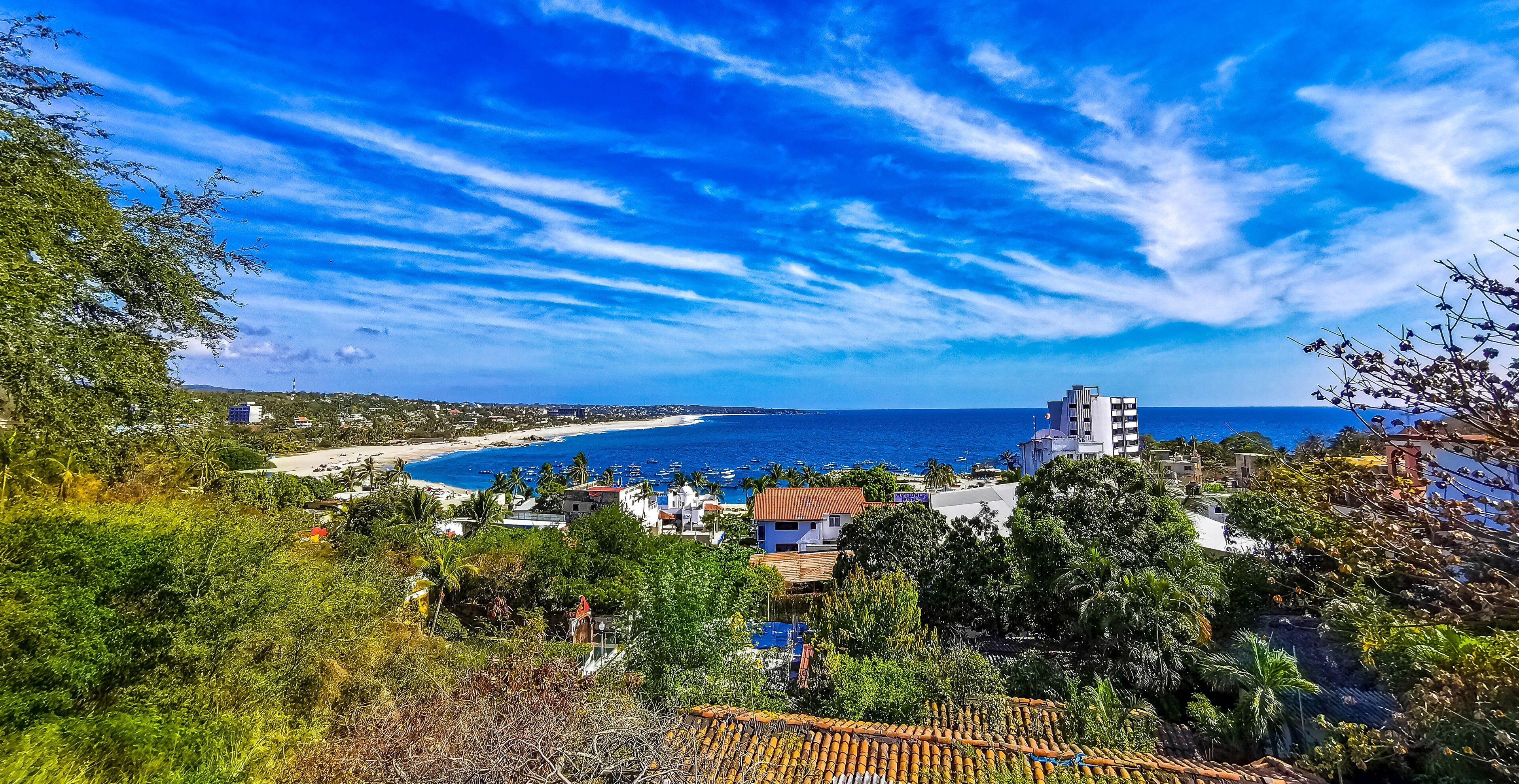 A coastal town with a beach, ocean, and clear blue sky.