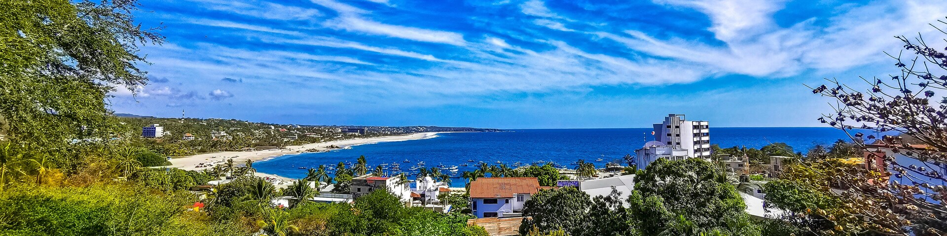 A coastal town with a beach, ocean, and clear blue sky.