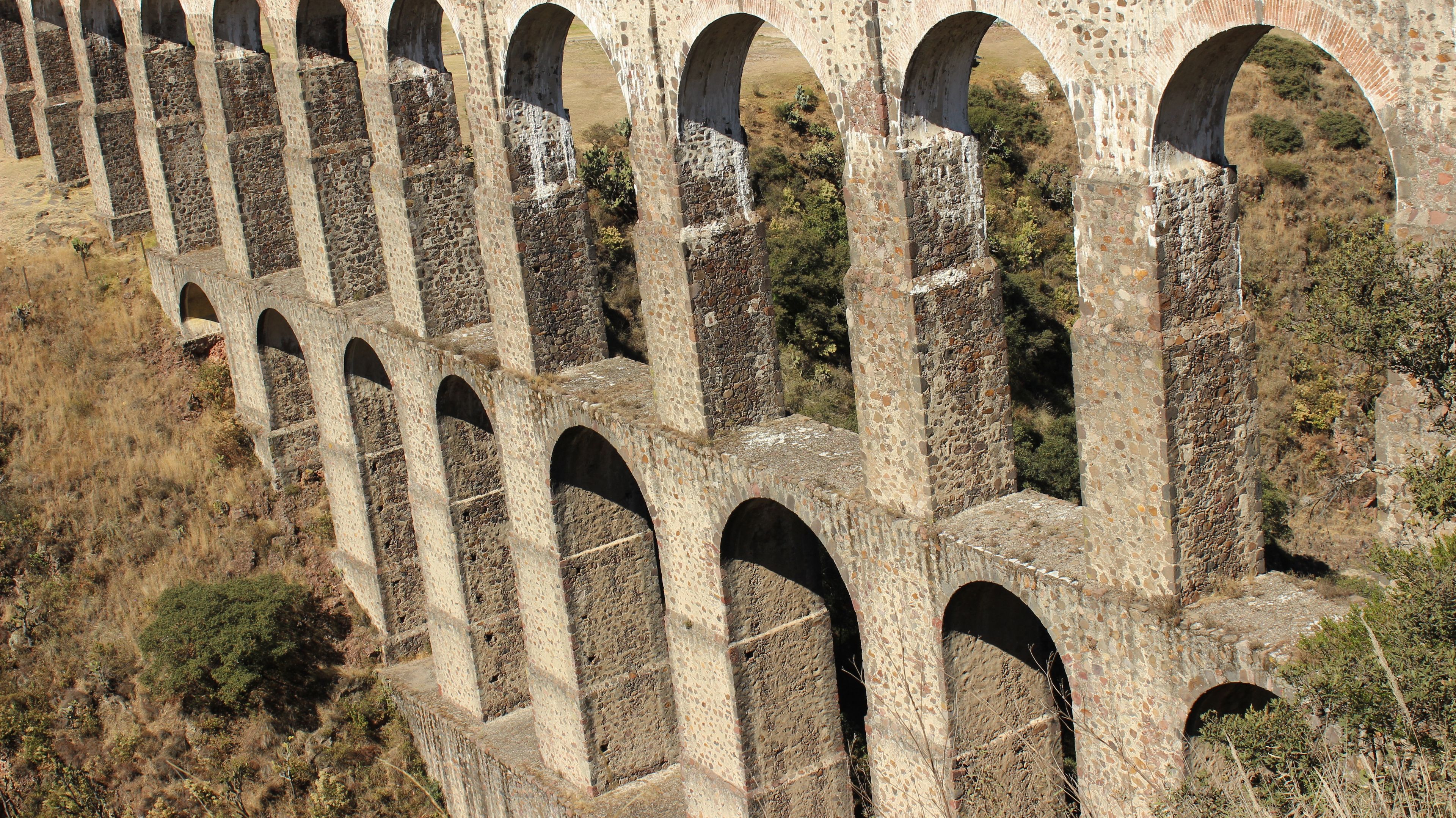 Una serie de arcos de piedra en un paisaje seco y montañoso.