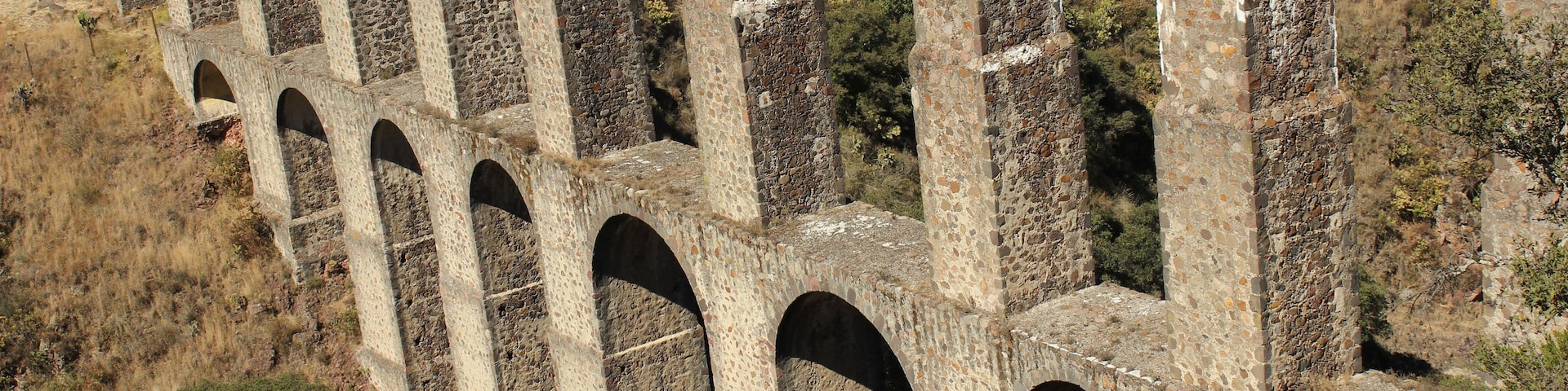 Una serie de arcos de piedra en un paisaje seco y montañoso.