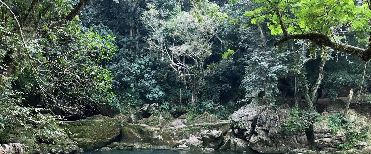 A clear turquoise river surrounded by large rocks and lush greenery.