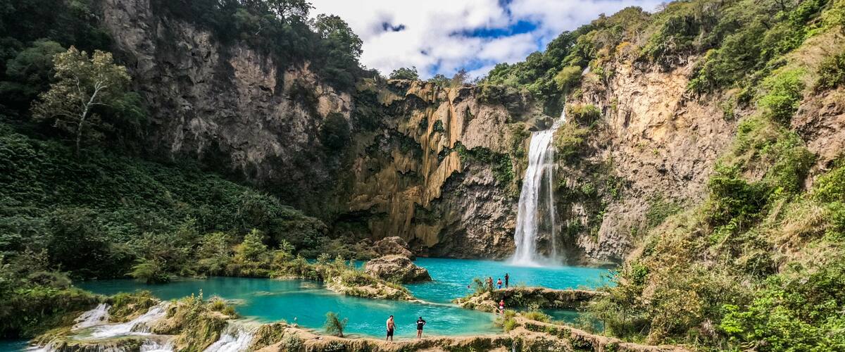 A turquoise river with waterfalls and rocky terrain.