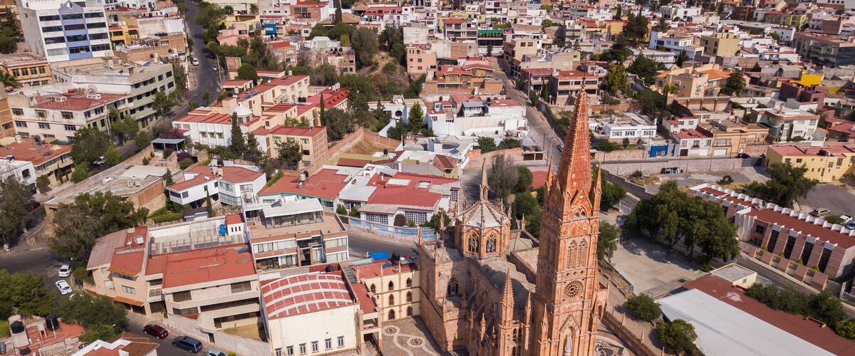 An aerial view of a city with a prominent church featuring a tall spire and intricate architecture.