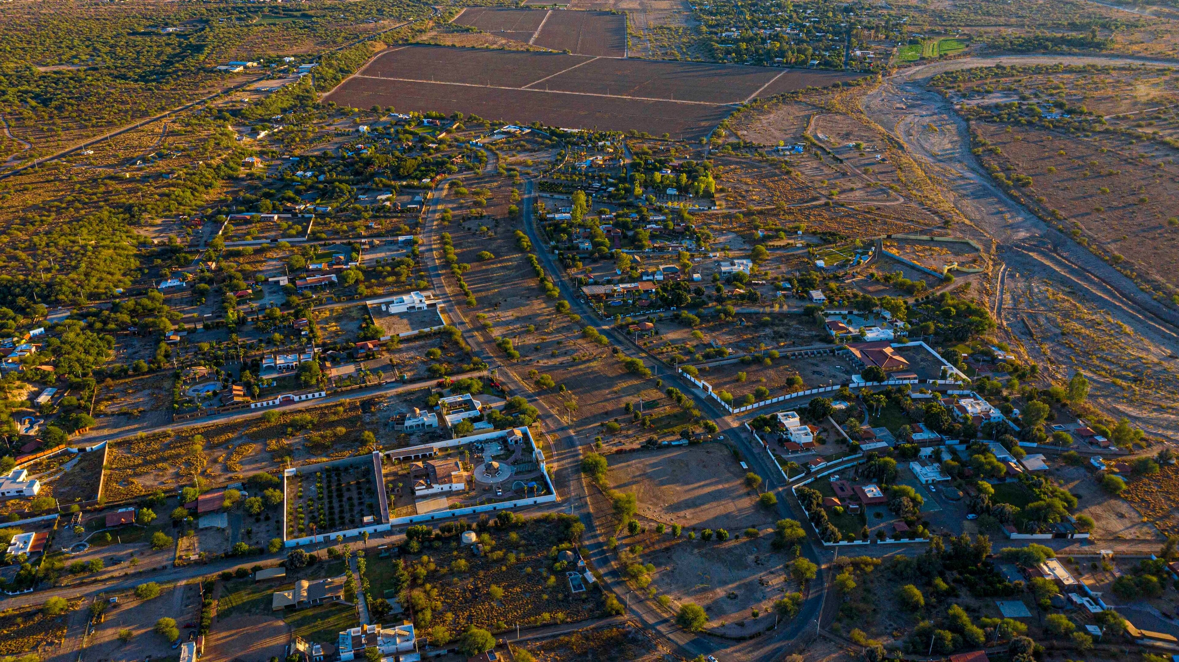 An aerial view of a town with a mix of residential and agricultural areas, roads, and scattered buildings.