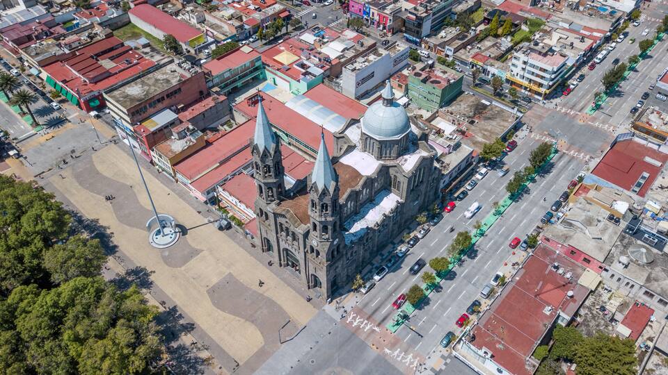 An aerial view of a city with a prominent church with a large dome and spires, surrounded by various buildings and streets.
