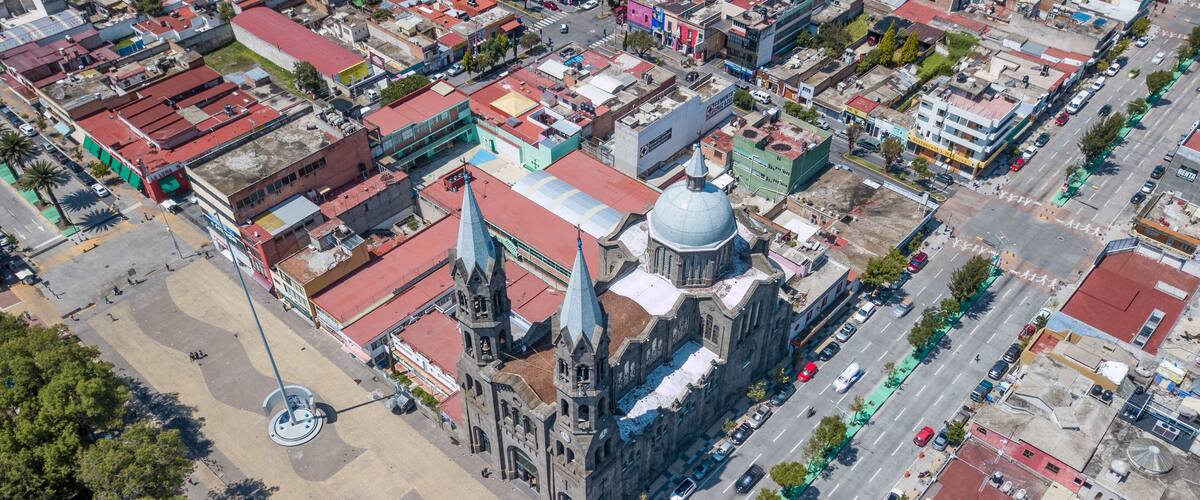 An aerial view of a city with a prominent church with a large dome and spires, surrounded by various buildings and streets.