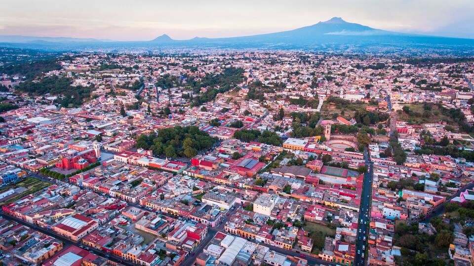 An aerial view of a city with a prominent volcano in the background.