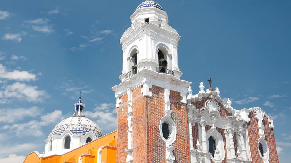 A white church with a bell tower and a dome, adjacent to a yellow building.