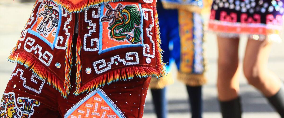 A person in a colorful traditional costume with intricate patterns and a large headdress.