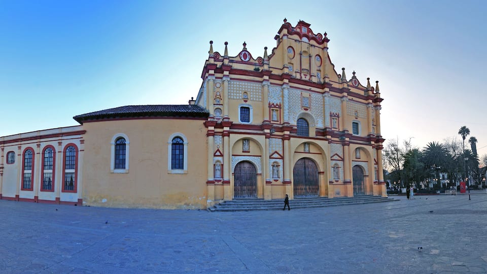 A historic church with ornate architecture and a large open plaza in front.