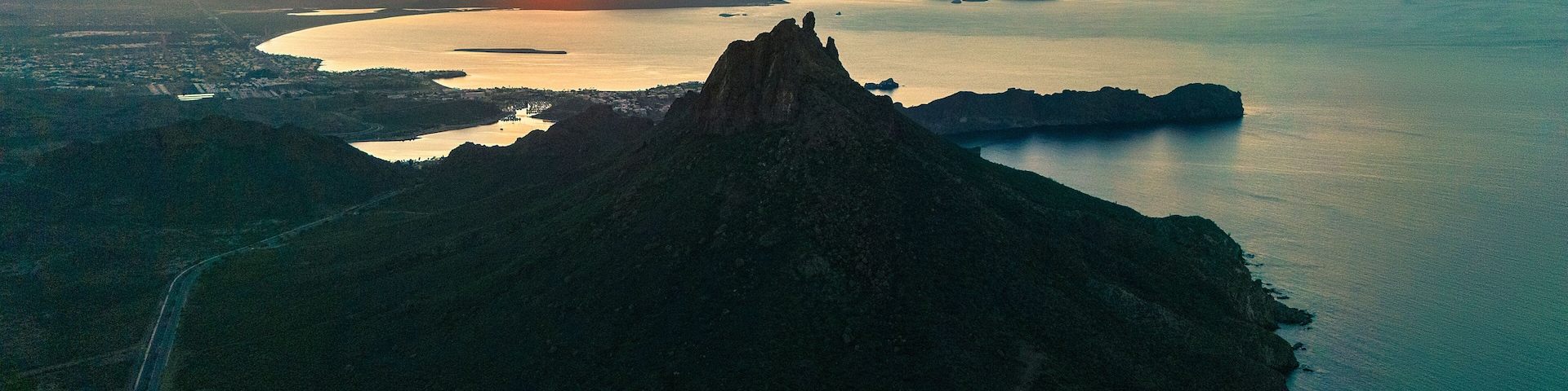 Spectacular aerial shot of the sunrise. The sun rises over the horizon illuminating the calm bay of San Carlos Sonora, Mexico and its iconic Tetakawi mountain.default