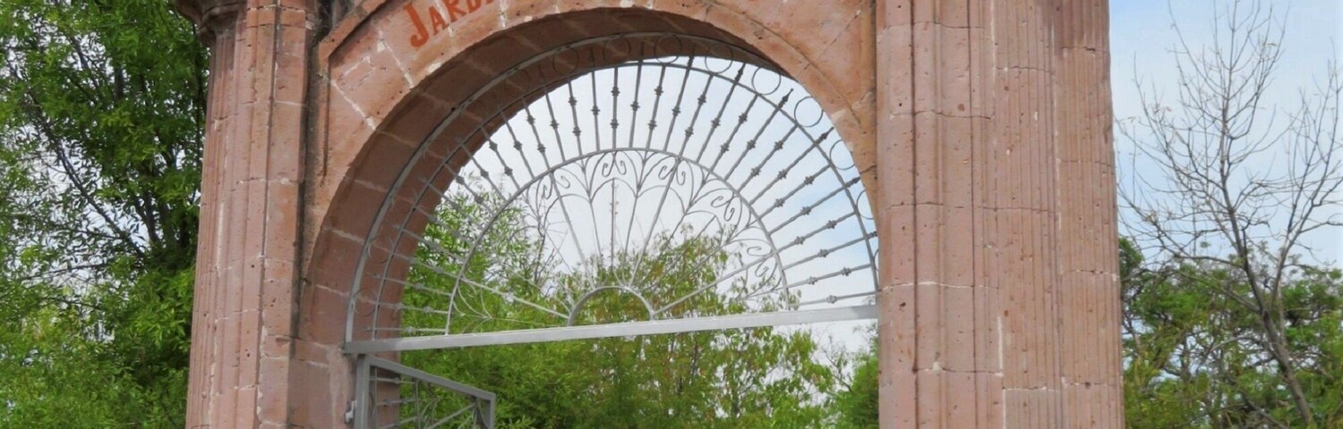 Un arco de piedra ornamentado con la inscripción 'JARDIN DE S.N. MARCOS' y una reja de metal.