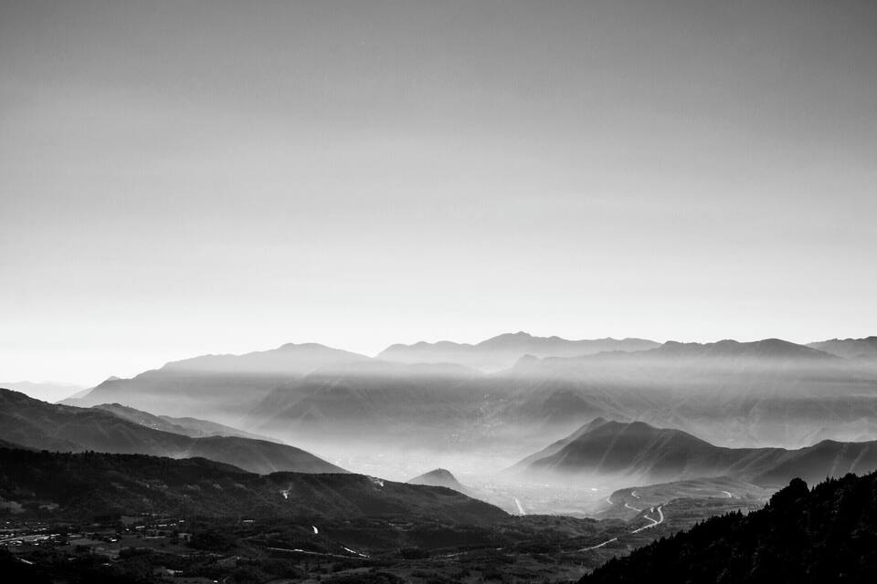 A mountainous landscape with a valley and winding roads.