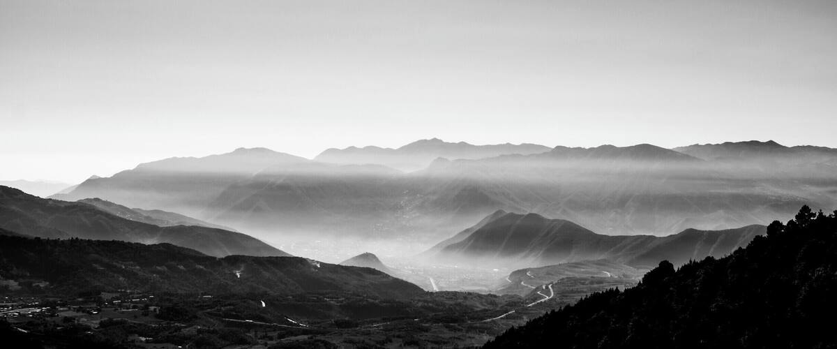A mountainous landscape with a valley and winding roads.