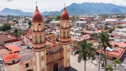 Orizaba, Veracruz, Mexico - July 14, 2022: Surrounded by mountains, cloudy sun shines on the historic core and churches of downtown Orizaba.