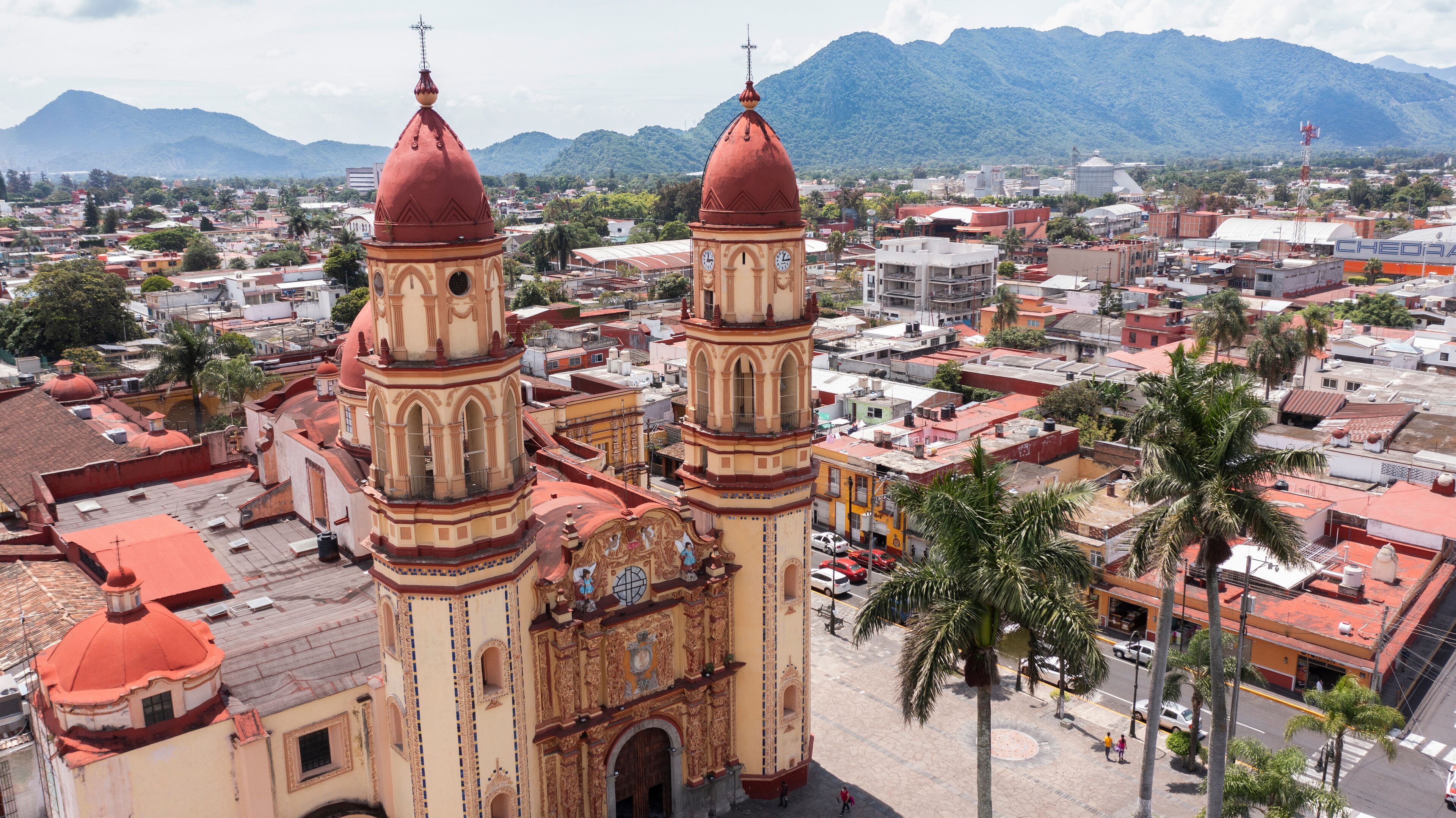 A historic church with two prominent towers and a mountainous backdrop.