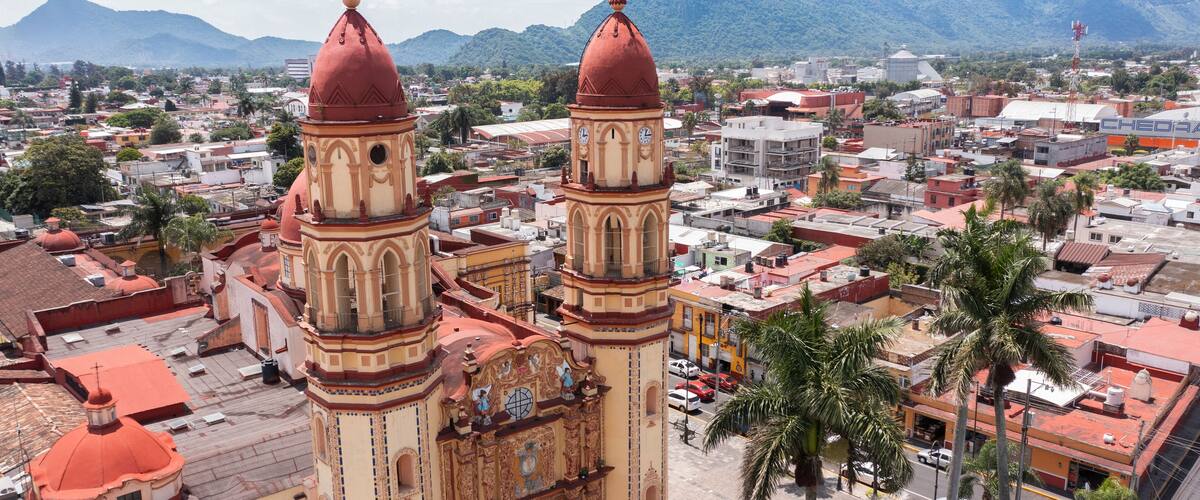 A historic church with two prominent towers and a mountainous backdrop.