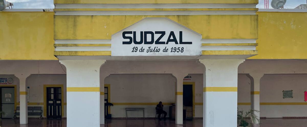 A building with a clock and a sign reading 'SUDZAL 19 de Julio de 1958'.