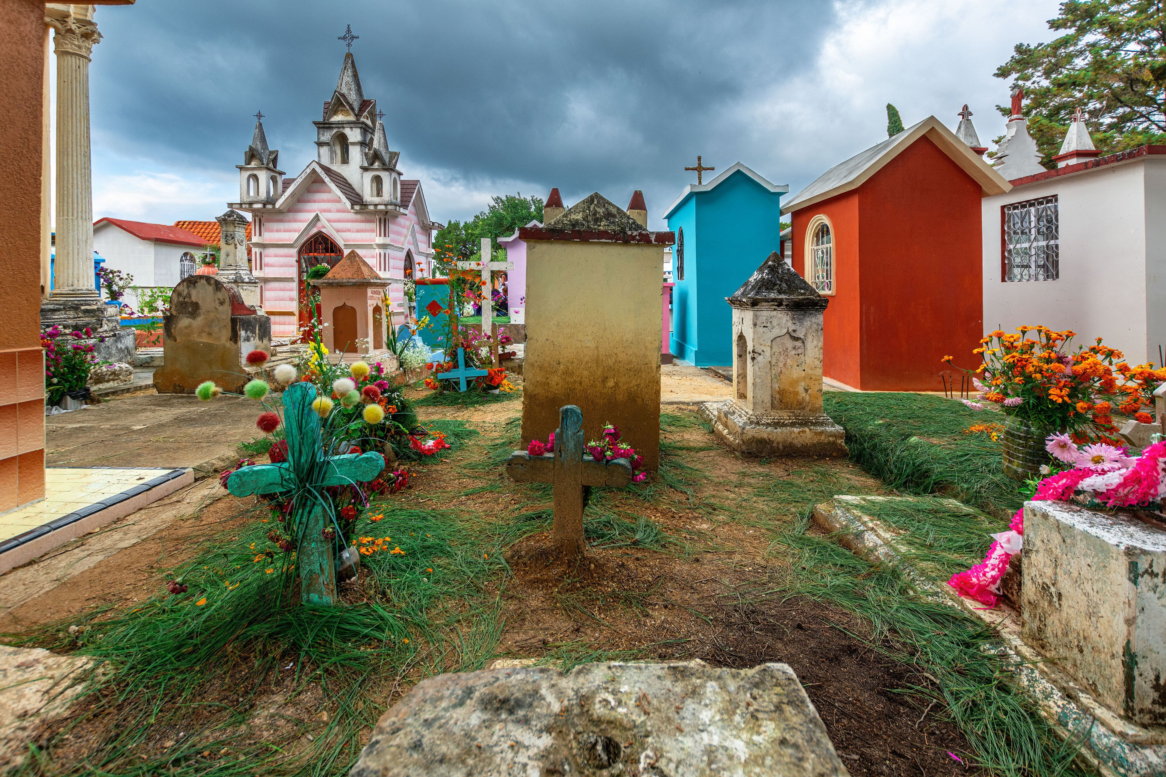 A cemetery with colorful tombstones and a church in the background.