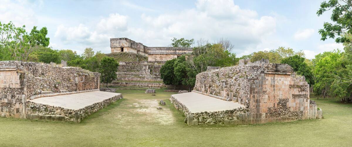 An ancient Mayan temple complex with stone structures and a central courtyard.