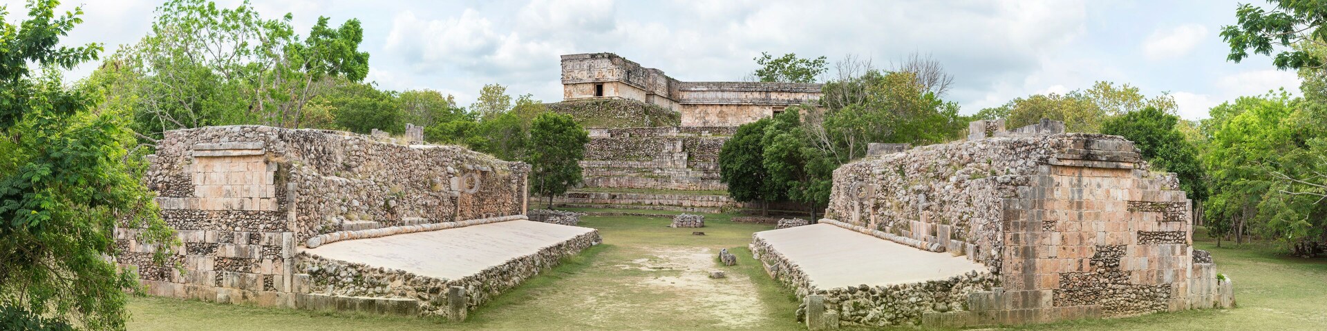 An ancient Mayan temple complex with stone structures and a central courtyard.