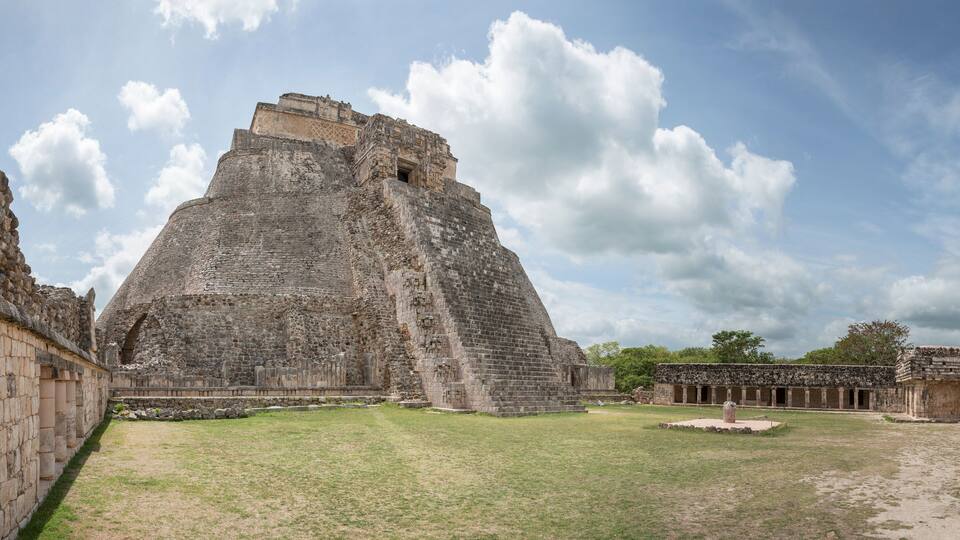A large pyramid structure surrounded by stone walls and a clear sky.