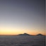 A mountain range silhouetted against a sunset sky, with a sea of clouds below.