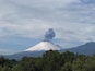 A snow-capped mountain with a plume of smoke rising from its peak.