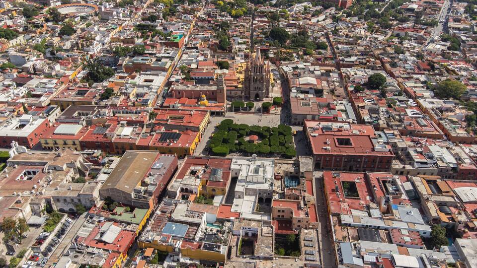 the church Parroquia Archangel Jardin Town Square Night Tree Decoraciones San Miguel de Allende, México. Parroaquia. Night and morning light in a drone view.
