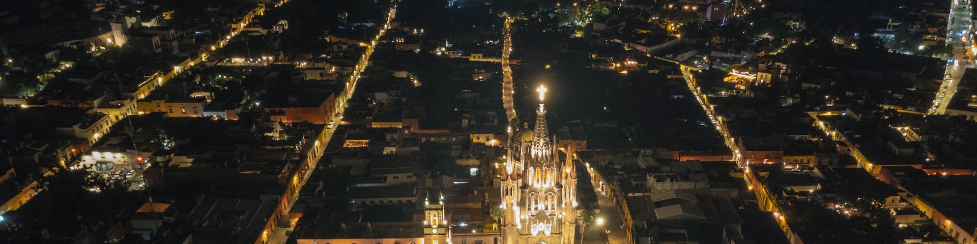 the church Parroquia Archangel Jardin Town Square Night Tree Decoraciones San Miguel de Allende, México. Parroaquia. Night and morning light in a drone view.