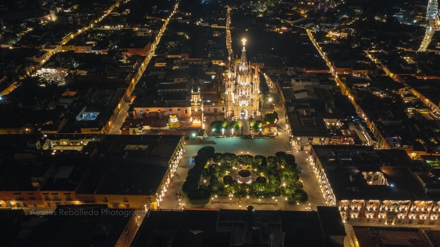 the church Parroquia Archangel Jardin Town Square Night Tree Decoraciones San Miguel de Allende, México. Parroaquia. Night and morning light in a drone view.
