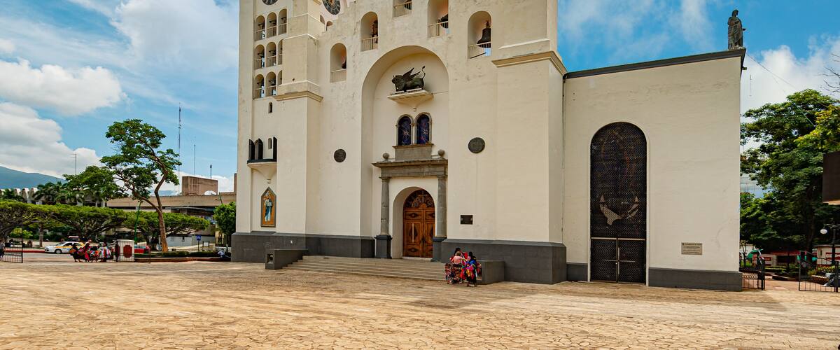 A historic church with a large arched entrance, a bell tower, and a statue on top.