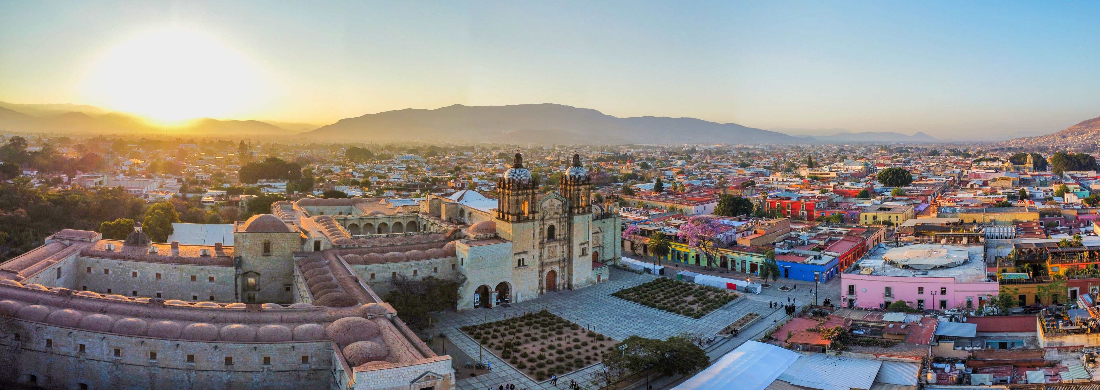 A historic cityscape with a prominent cathedral, a large open square, and a mountainous backdrop.