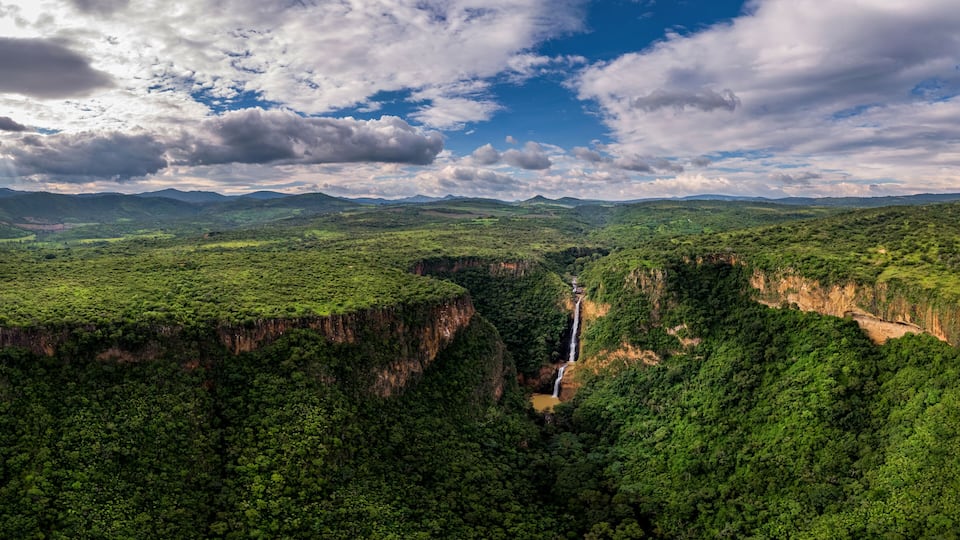 A lush green valley with a waterfall and a river.