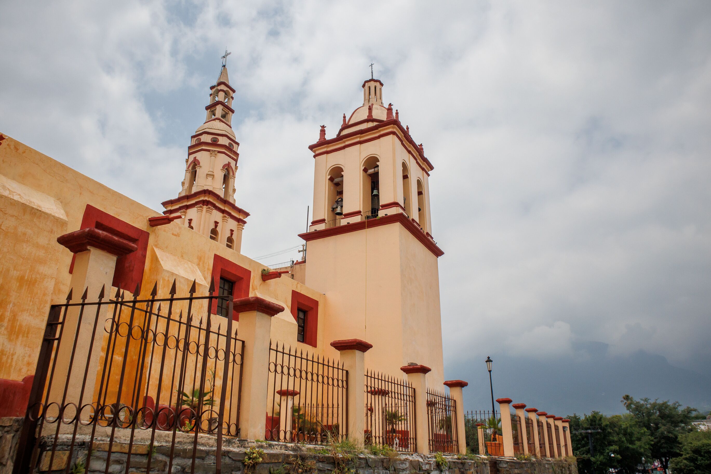 A historic church with a bell tower and a fence in front.