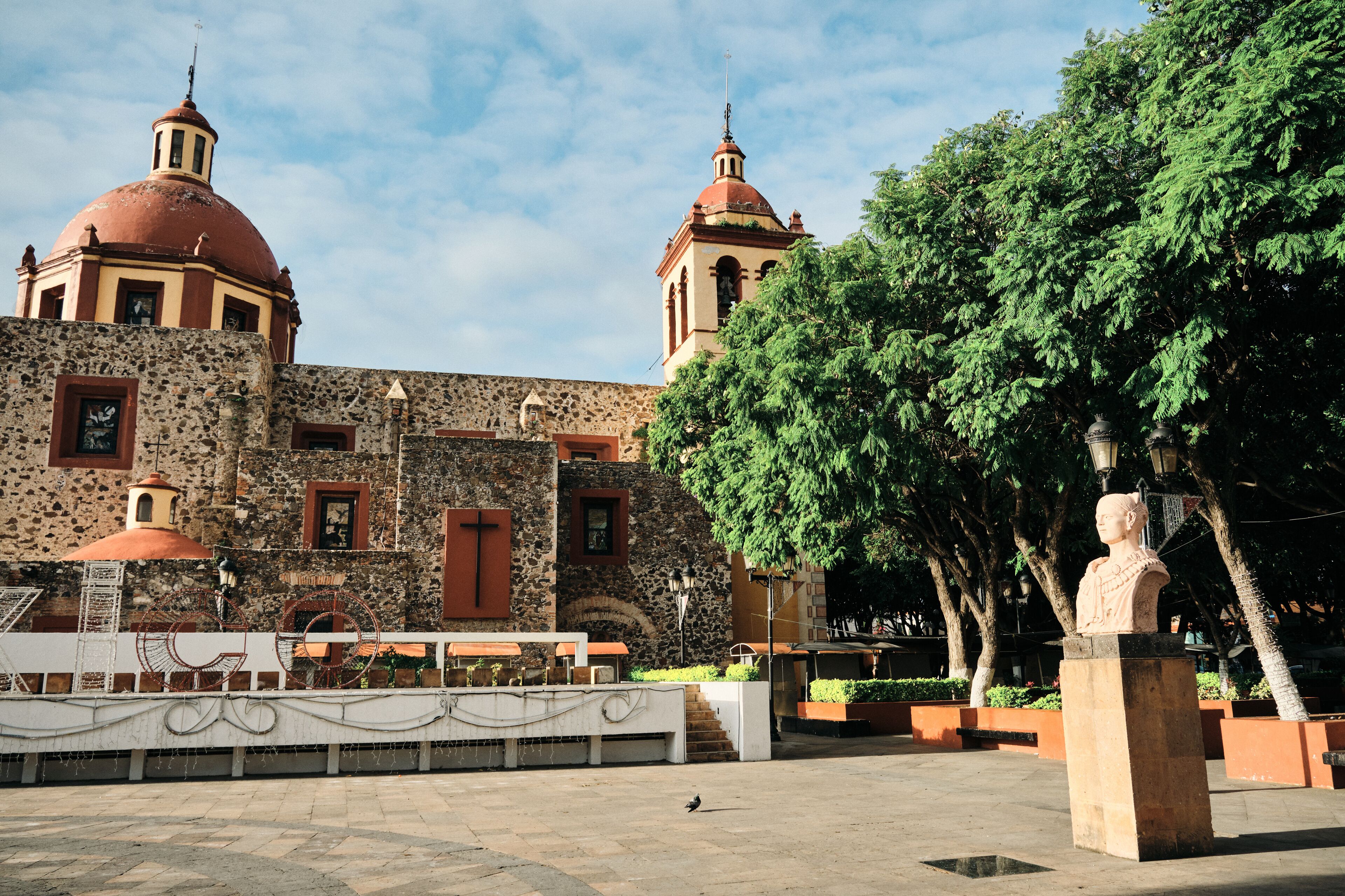 A historic building with two domed towers, a stone facade, and a statue in the foreground.