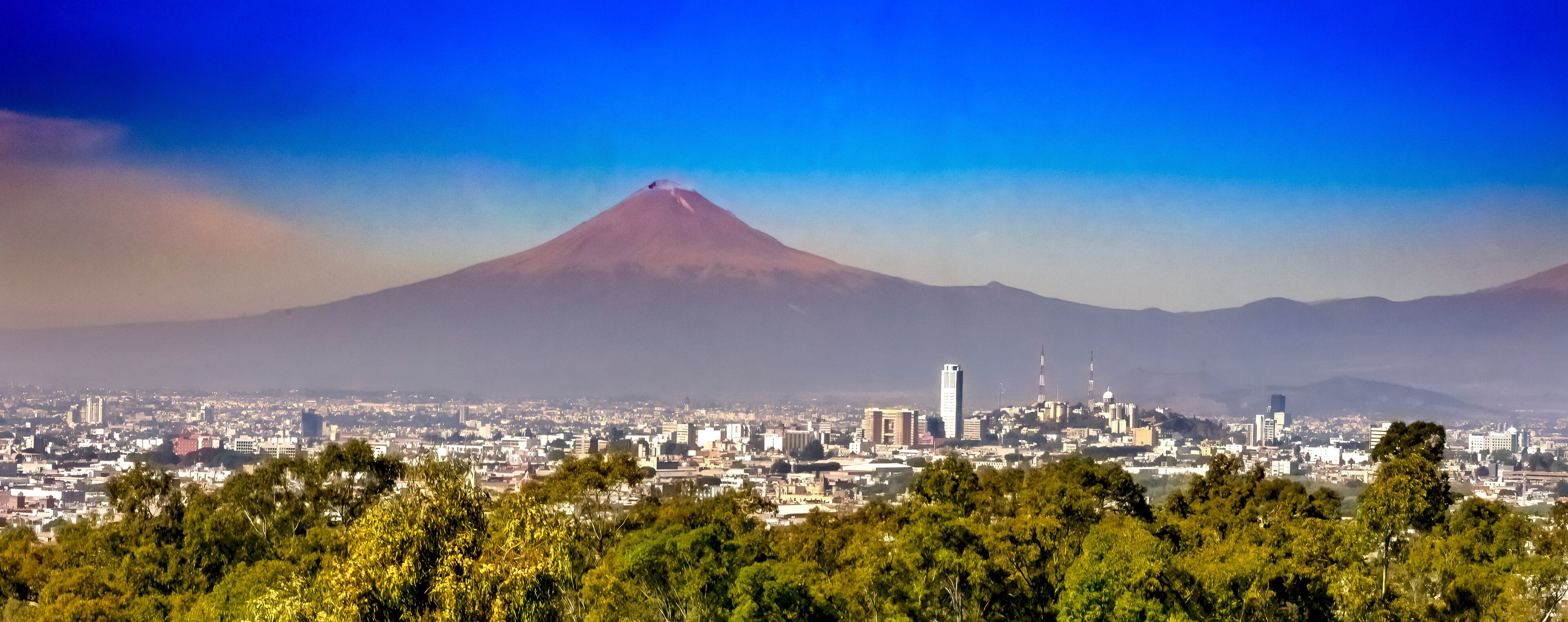 A cityscape with a prominent volcano in the background.