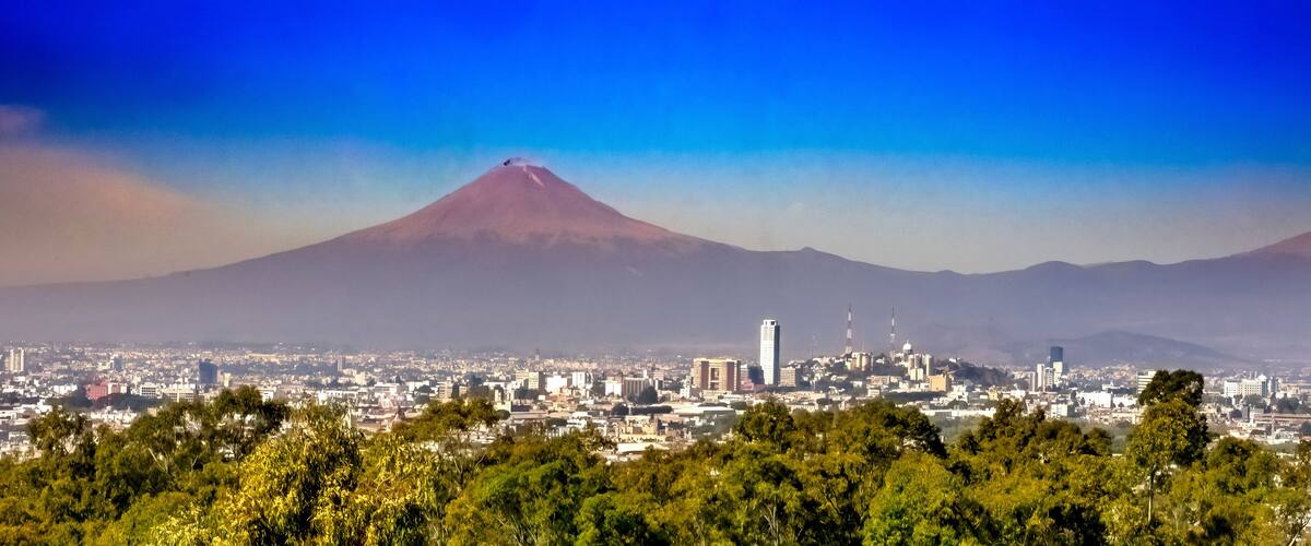 A cityscape with a prominent volcano in the background.