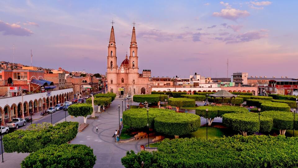 A historic cityscape with a prominent church, a well-maintained public square, and surrounding urban architecture.