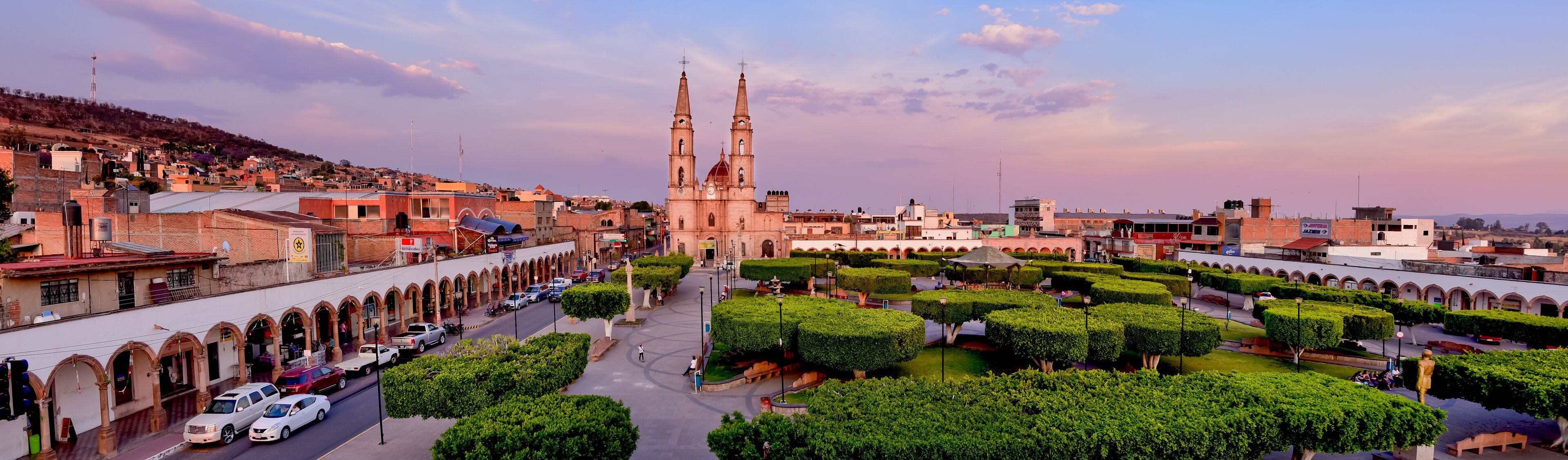 A historic cityscape with a prominent church, a well-maintained public square, and surrounding urban architecture.