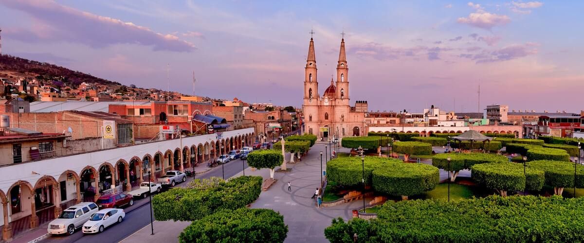 A historic cityscape with a prominent church, a well-maintained public square, and surrounding urban architecture.