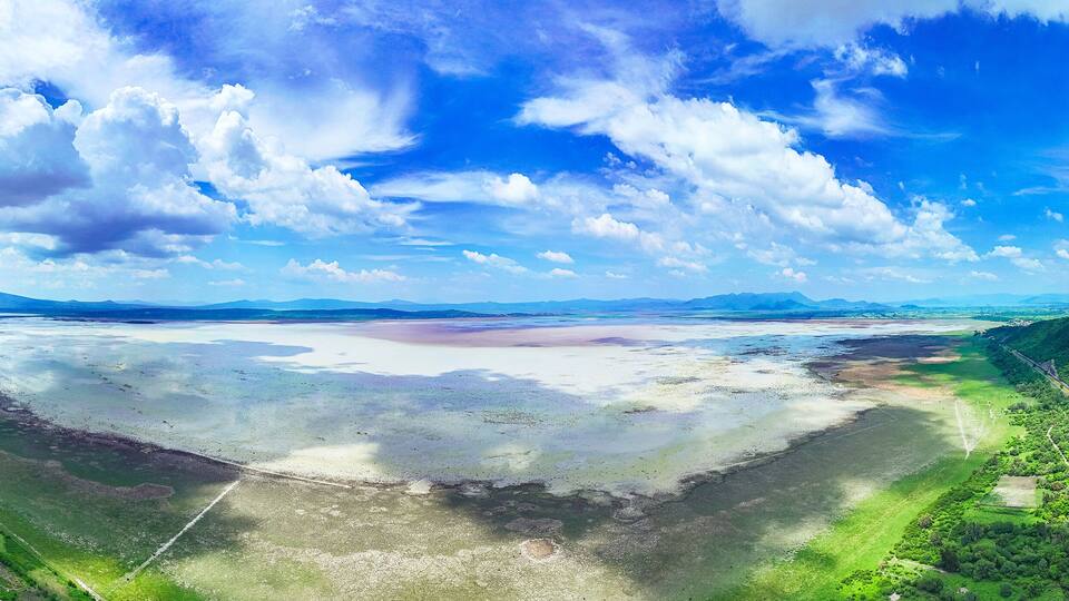Drought-stricken Lake Cuitzeo, Michoacán: Parched shores and barren banks reveal the lake's severe water scarcity, contrasting with a nearby road and arid landscape