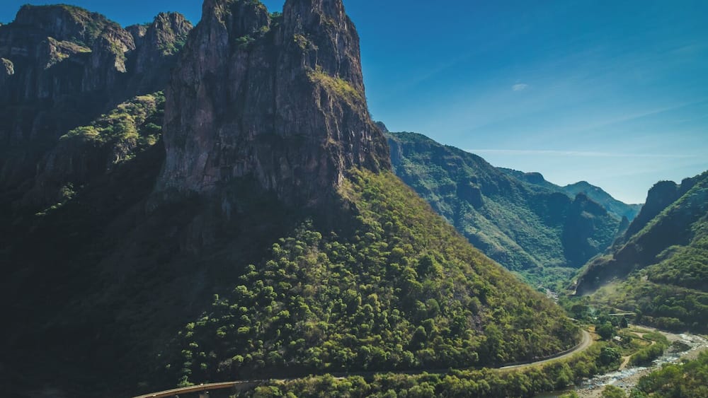 Un paysage montagneux, avec une rivière sinueuse et un pont.