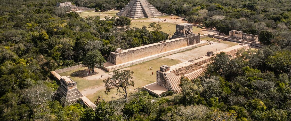 An ancient Mayan pyramid complex surrounded by dense forest.