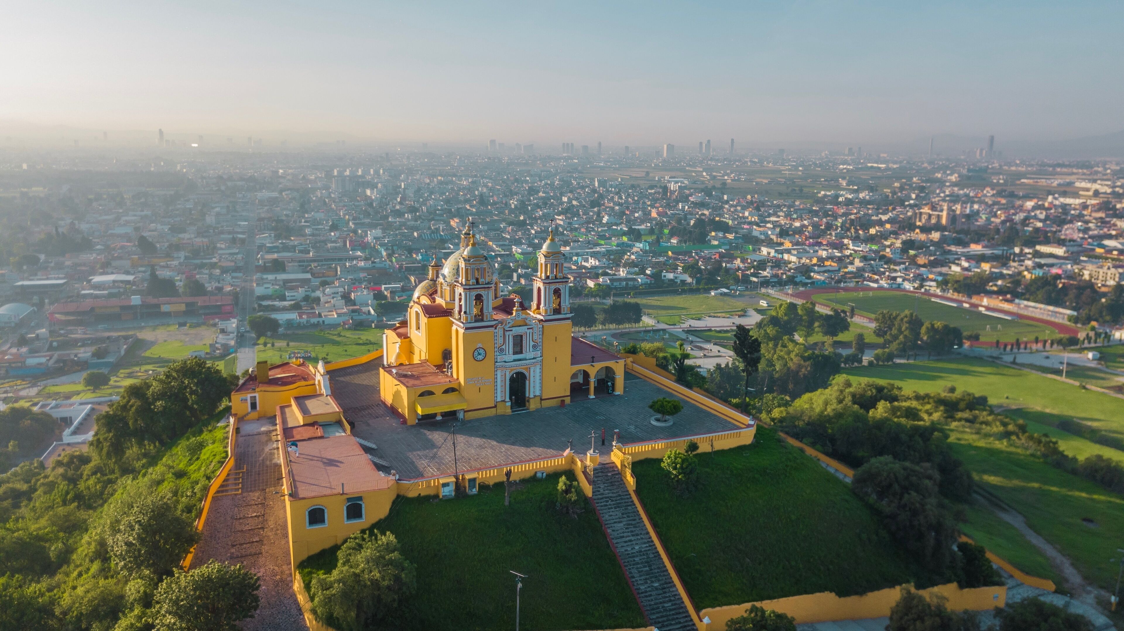 An aerial view of a city with a prominent yellow church featuring two towers and a large dome.