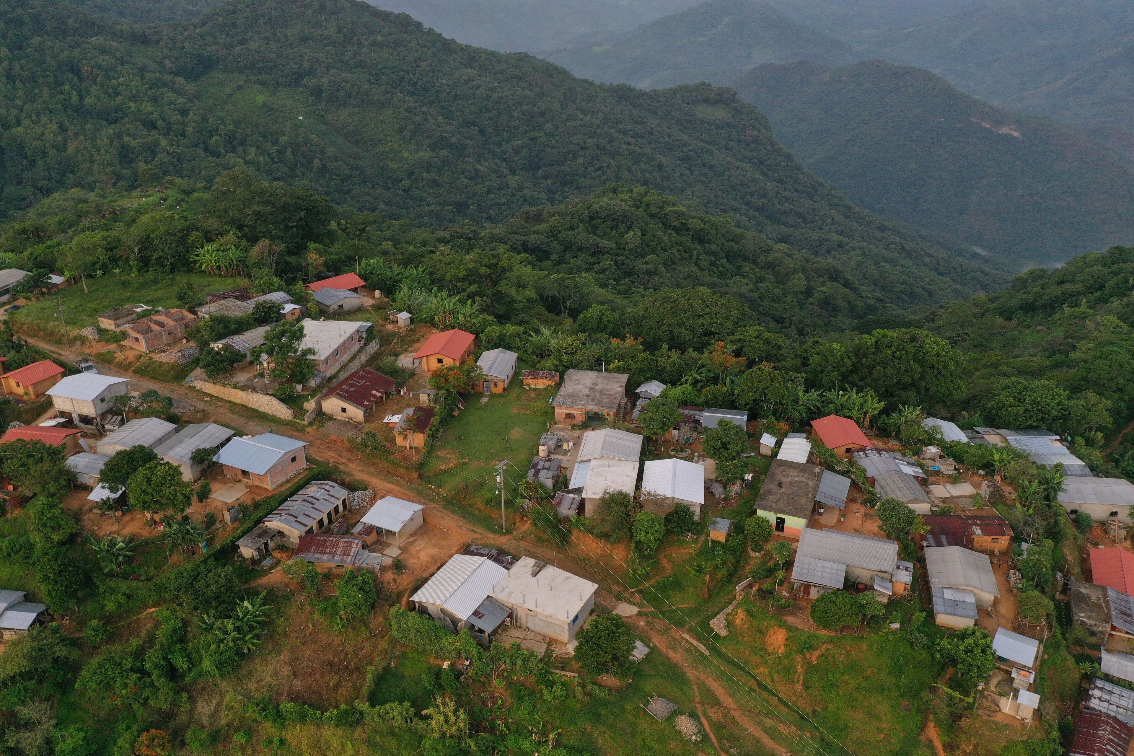 An aerial view of a rural village with houses and lush greenery.