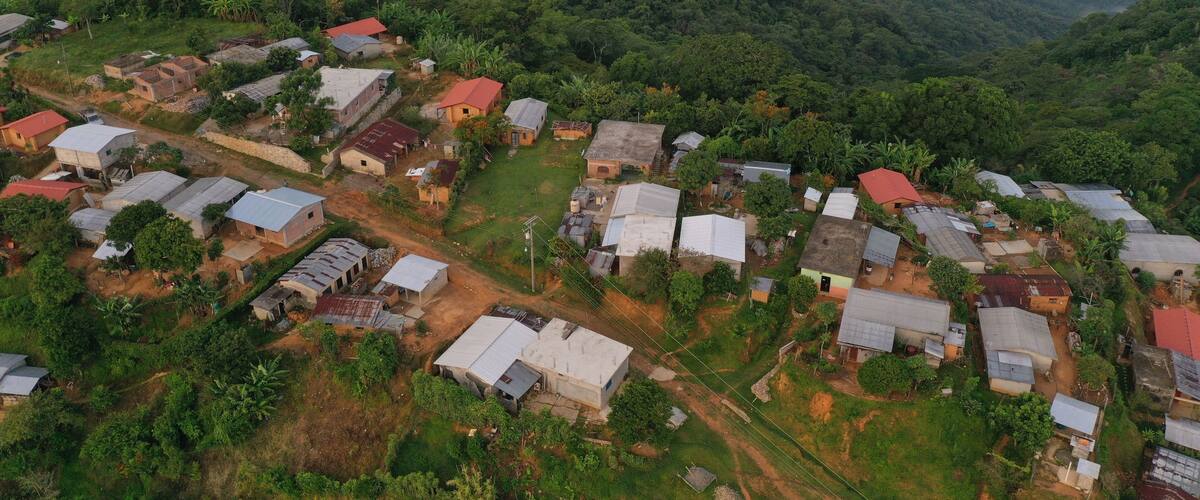 An aerial view of a rural village with houses and lush greenery.