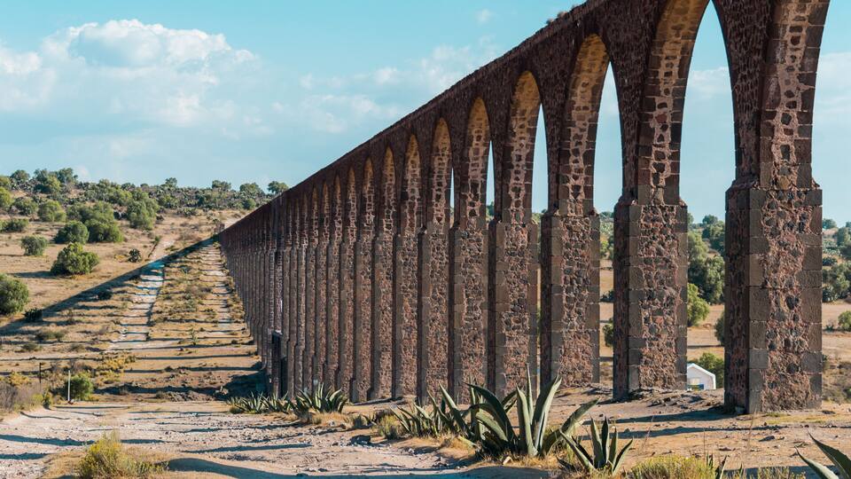 A long stone viaduct with multiple arches spanning a dry, hilly landscape.